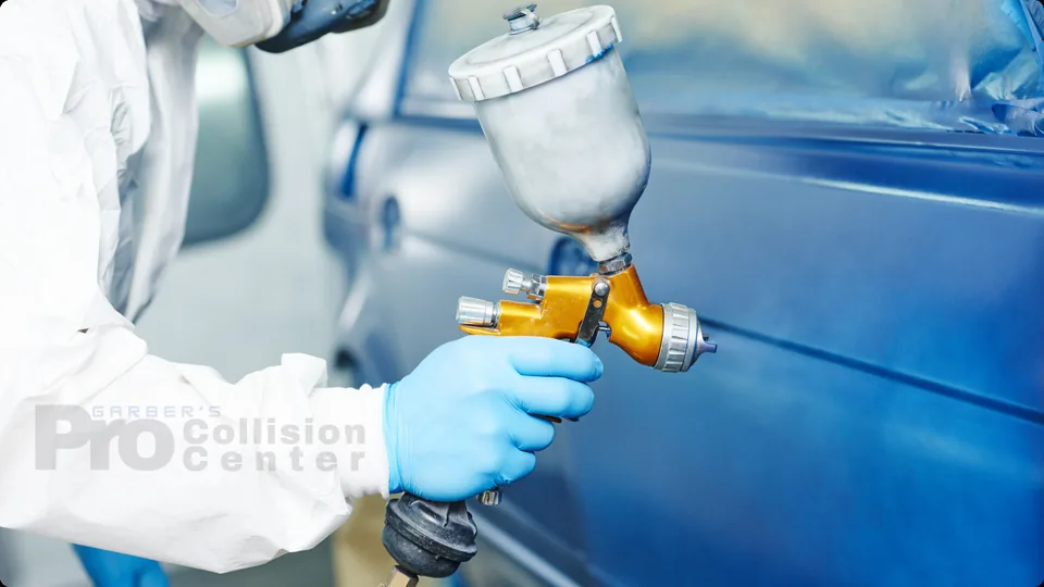 Technician spray painting a blue car door